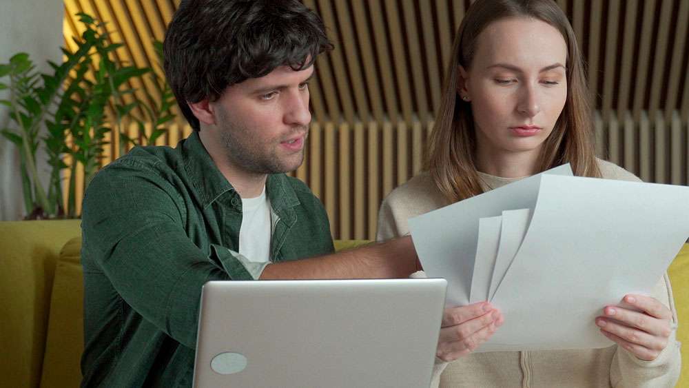 Serious young couple considering buying a home, going over facts and listings.