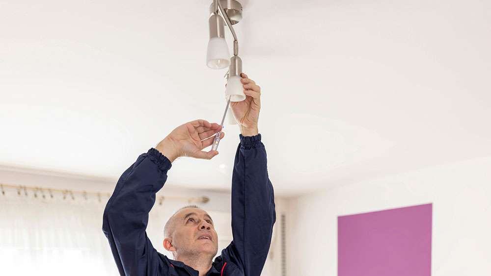 Man replaces a defective ceiling light.