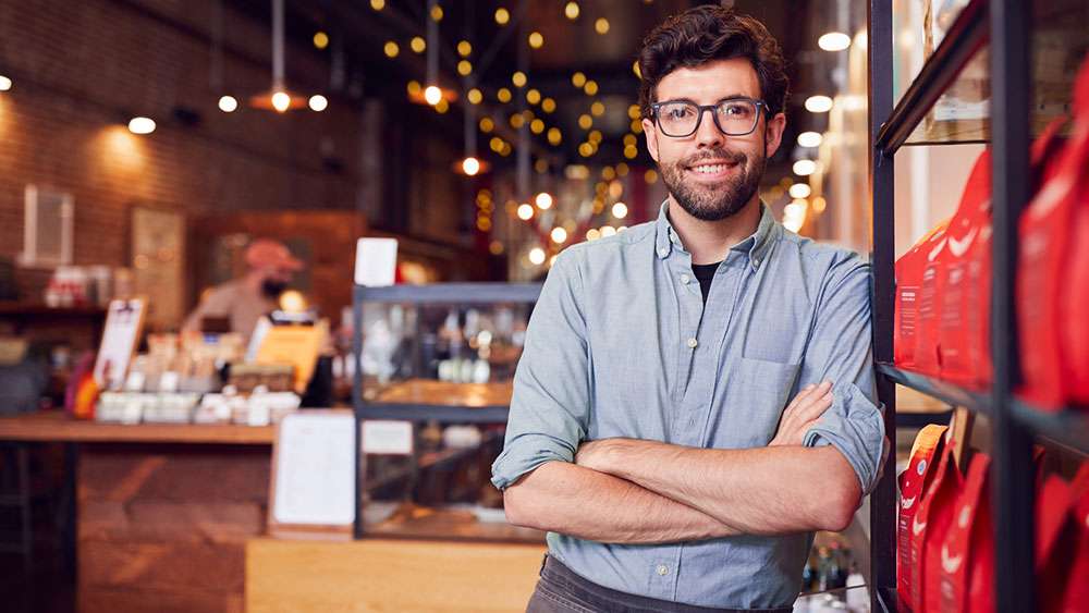 Small business coffee shop owner standing by the shop door.