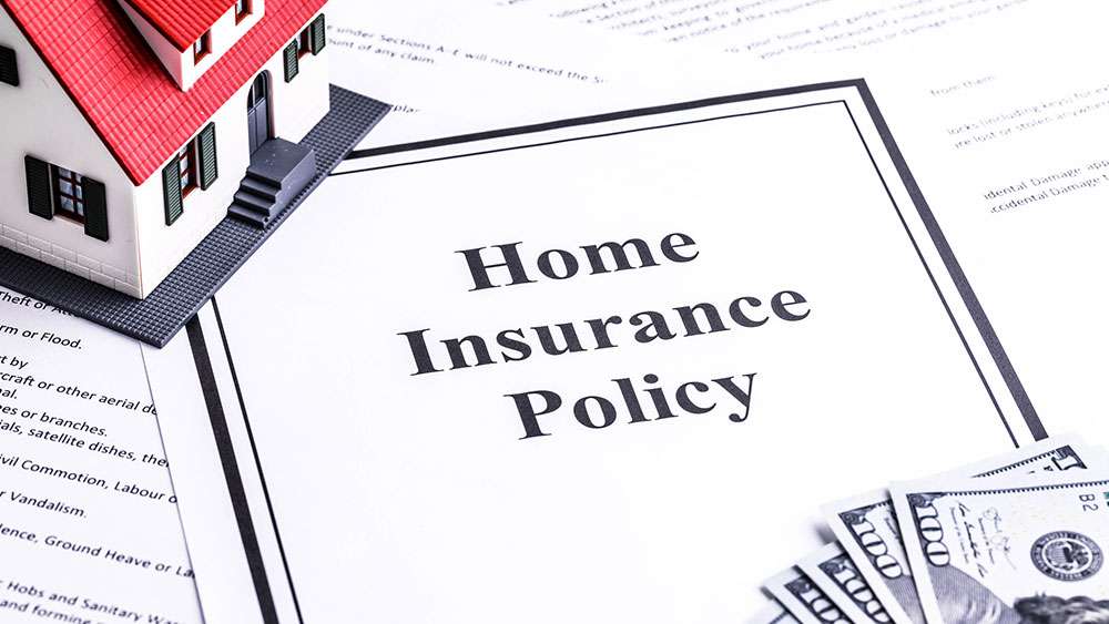 Home insurance policy on a table with a model house and money