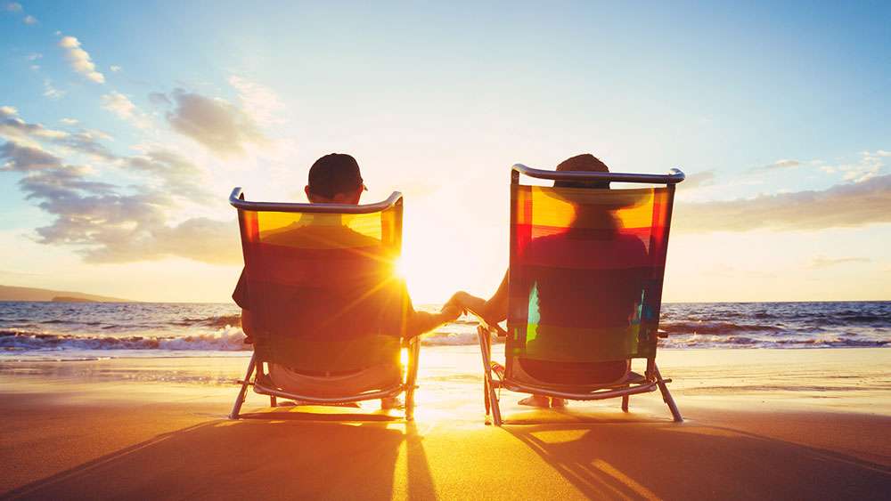 Retired couple on beach watching the sunset