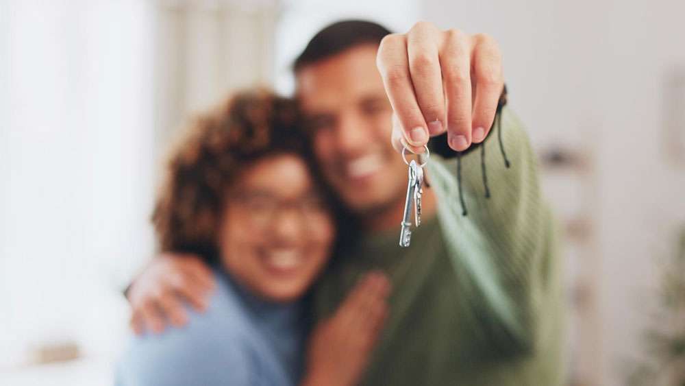 Smiling young couple shows keys to their new home