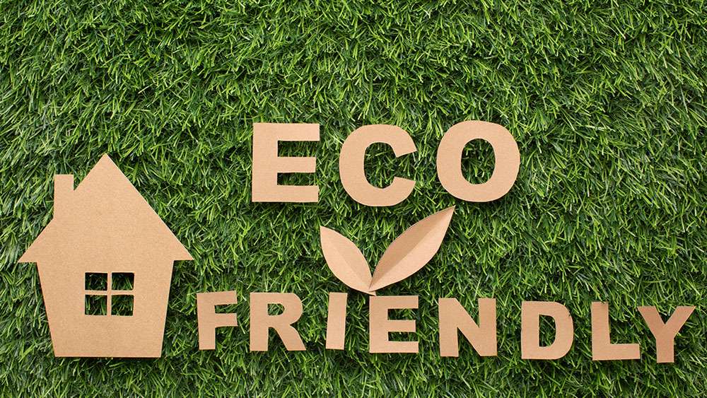 Miniature house and eco-friendly sign on a lawn